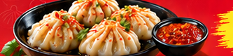 Plate of steaming momos with spicy red sauce